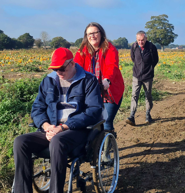 staff pushing person in wheelchair on a walk
